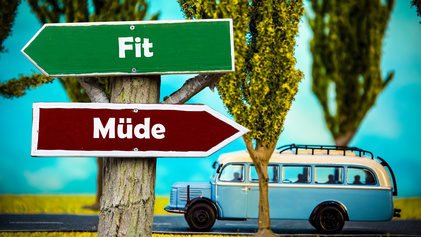Schilder Fit Müde an Baum vor altem Wohnmobil